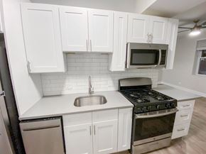 Chicago apartment for rent - A kitchen with white cabinets and a black stove top oven.