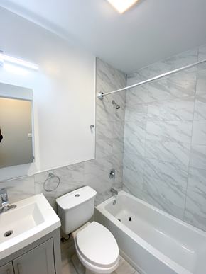Chicago apartment for rent - A white toilet sits next to a sink in a bathroom.