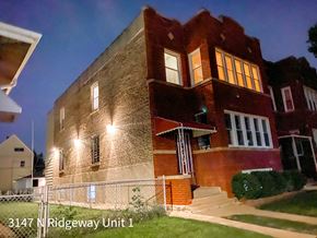 Chicago apartment for rent - A brick building with the address 3147 N Ridgeway Unit 1 is shown at night.