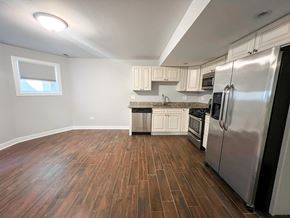 Chicago apartment for rent - A kitchen with a stainless steel refrigerator and wooden flooring.