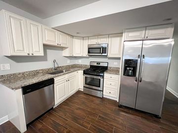 Chicago apartment for rent - A kitchen with white cabinets and a granite countertop.