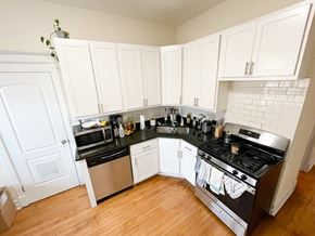 Chicago apartment for rent - A kitchen with white cabinets and black countertops.