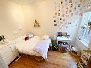 Chicago apartment for rent - A bedroom with a bed, nightstand, and a wall covered in postcards.
