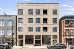 Chicago apartment for rent - A modern building with a beige facade stands between two older buildings.