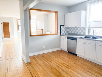 Chicago apartment for rent - A kitchen with white cabinets and a wooden floor.