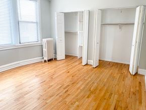 Chicago apartment for rent - A room with wooden floors and white walls with a window and a radiator.