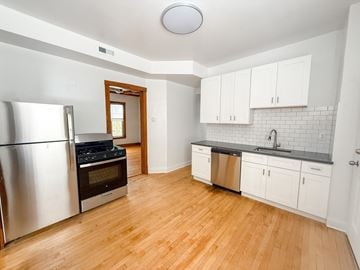 Chicago apartment for rent - A kitchen with a stainless steel refrigerator and wooden floors.