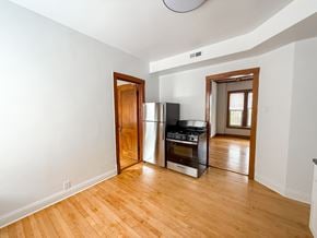 Chicago apartment for rent - A kitchen with a stove and refrigerator in a room with wooden floors.