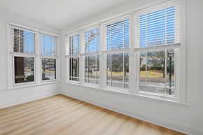 Evanston apartment for rent - A room with white walls and wooden flooring, featuring a large window with white blinds.