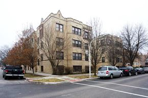 Chicago apartment for rent - an apartment building with cars parked in a parking lot