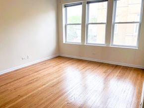 Chicago apartment for rent - an empty room with wooden floors and three windows