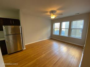Chicago apartment for rent - an empty living room with a refrigerator and a ceiling fan