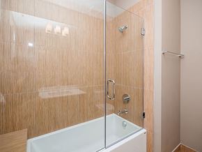 Chicago apartment for rent - A modern bathroom with a glass shower door and a white bathtub.