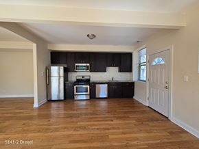 Chicago apartment for rent - an empty kitchen with black cabinets and a wooden floor