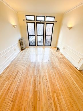 Chicago apartment for rent - A room with wooden floors and a large window.