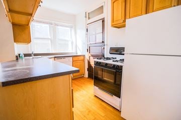 Chicago apartment for rent - A kitchen with a white refrigerator and a black countertop.