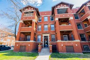 Chicago apartment for rent - A red brick apartment building with a black car parked in front.