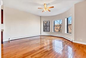 Chicago apartment for rent - an empty living room with hardwood floors and a ceiling fan