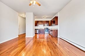 Chicago apartment for rent - an empty living room and kitchen with wood flooring and a ceiling fan