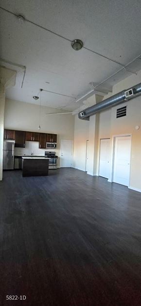 Chicago apartment for rent - A large empty room with a kitchen area in the background.