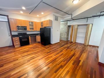 Evanston apartment for rent - A kitchen with wooden floors and a black refrigerator.