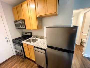 Chicago apartment for rent - A kitchen with a black refrigerator, stainless steel sink, and wooden cabinets.