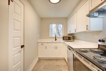 Denver apartment for rent - A kitchen with white cabinets and a stainless steel stove.