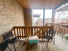 Chicago apartment for rent - A wooden balcony with a box and chairs.
