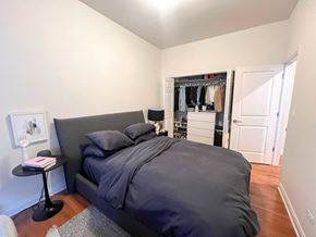 Chicago apartment for rent - A bedroom with a large bed and a small table with a book on it.