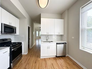 Chicago apartment for rent - A kitchen with white cabinets and a black stove top oven.