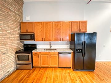 Chicago apartment for rent - A kitchen with wooden cabinets and a black fridge.