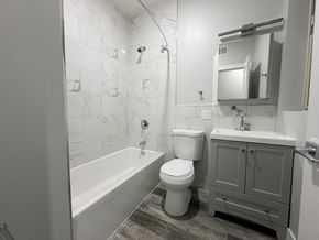 Chicago apartment for rent - A white toilet sits next to a bathtub in a bathroom.