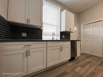 Chicago apartment for rent - A kitchen with white cabinets and a black and white tiled backsplash.