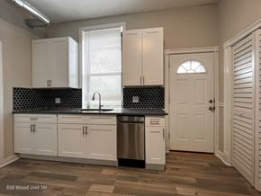 Chicago apartment for rent - A kitchen with white cabinets and a black and white tiled backsplash.
