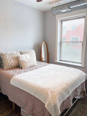 Chicago apartment for rent - A bed with a white comforter and a pillow with a white pillow case sits in a bedroom.