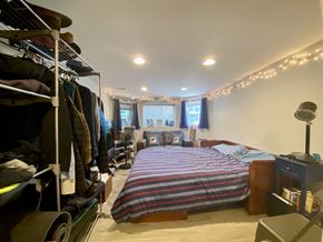 Chicago apartment for rent - A bedroom with a bed, a clothing rack, and a window with curtains.
