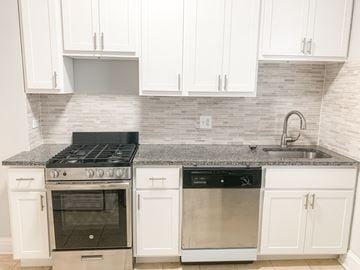 Chicago apartment for rent - A kitchen with white cabinets and a black stove top oven.