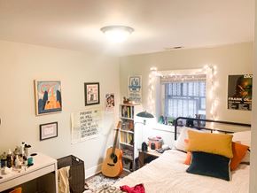 Chicago apartment for rent - A bedroom with a bed, a desk, a guitar, and a window with lights.