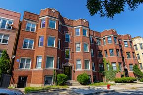 Chicago apartment for rent - A red brick building with a black gate in front.