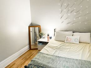 Chicago apartment for rent - A white bed with a grey blanket and a white pillow with a red design on it.
