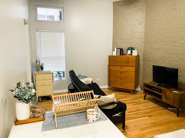 Chicago apartment for rent - A living room with a black chair and a wooden cabinet.