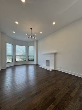 Chicago apartment for rent - A large empty room with a fireplace and wooden floors.