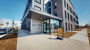 Denver apartment for rent - A modern building with a glass entrance and a sign that says "NOW LEASING".