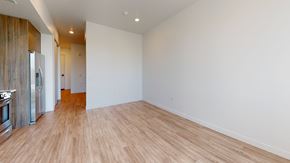 Denver apartment for rent - A spacious room with wooden flooring and white walls.