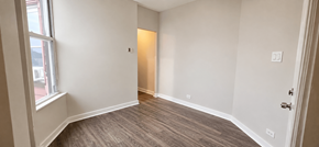 Chicago apartment for rent - A room with a wooden floor and white walls.