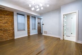 Chicago apartment for rent - A room with a brick wall and wooden flooring.