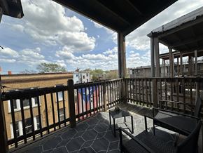 Chicago apartment for rent - A balcony with a bench and a table with a view of the sky and buildings.
