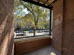 Chicago apartment for rent - A balcony with a brick wall and a metal railing overlooking a parking lot.