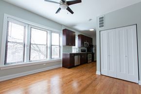 Chicago apartment for rent - A room with a ceiling fan and wooden floors.