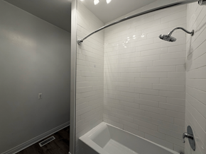 Chicago apartment for rent - A white tiled bathroom with a white tub and shower head.